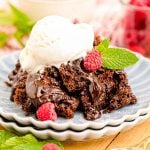 Close up of chocolate crockpot cake on blue scalloped plates on a wooden table.