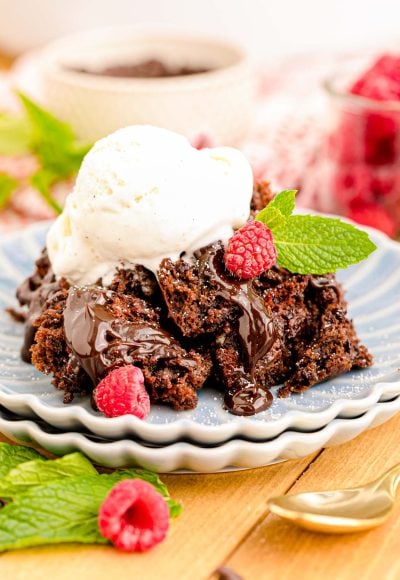 Close up of chocolate crockpot cake on blue scalloped plates on a wooden table.