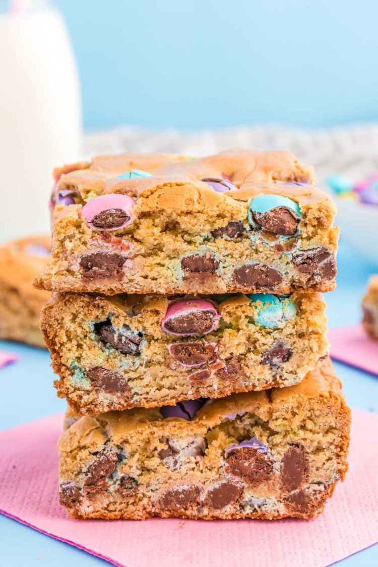 Close up of three easter blondie bars stacked on a pink napkin.