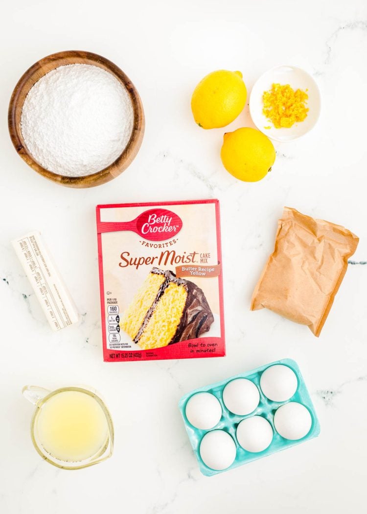 Ingredients to make lemon sheet cake with a box mix prepped on a marble surface.