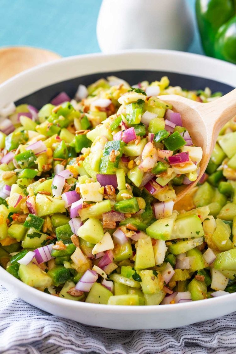 Close up photo of a serving spoon scooping salad out of a bowl.