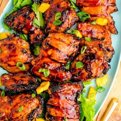 Close up photo of a blue platter with grilled huli huli chicken on it.