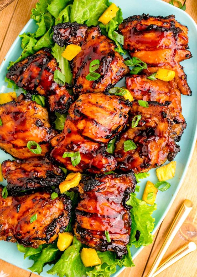 Close up photo of a blue platter with grilled huli huli chicken on it.