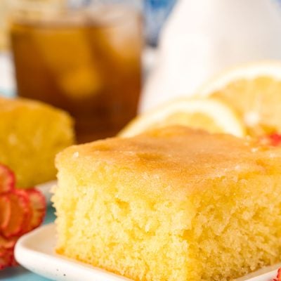 A slice of lemon drizzle cake on a white plate.