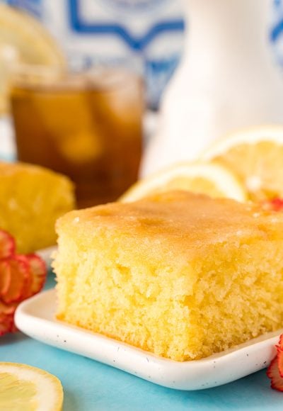 A slice of lemon drizzle cake on a white plate.