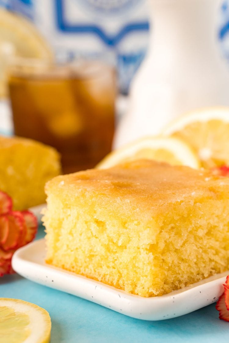 A slice of lemon drizzle cake on a white plate.