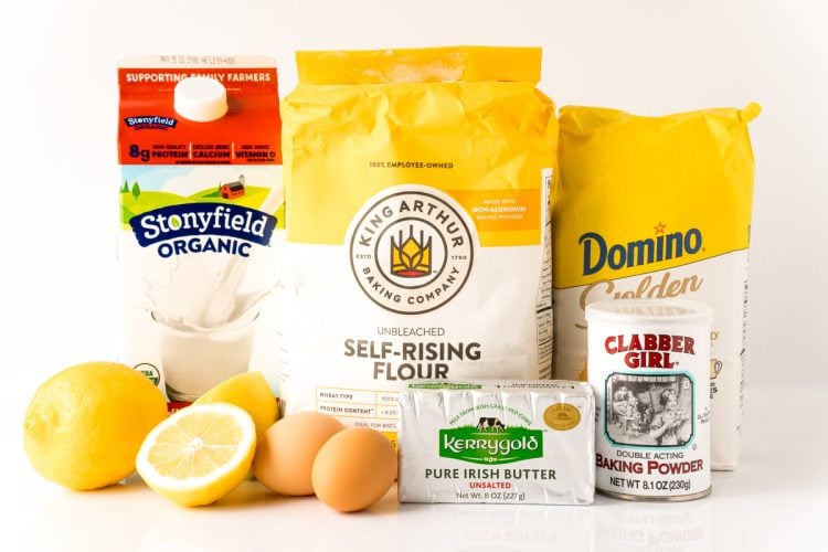 Ingredients to make lemon drizzle cake on a white table.