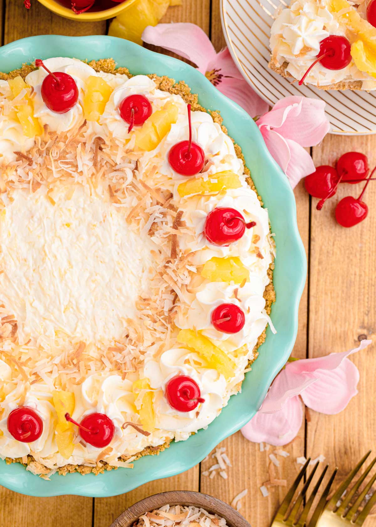 Overhead photo of a pina colada pie in a teal pie plate on a wooden table.
