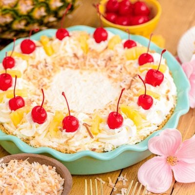 Pina colada pie in a teal pie dish on a wooden table.