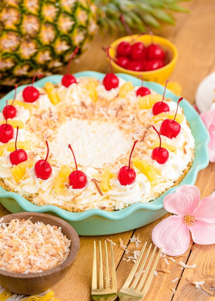 Pina colada pie in a teal pie dish on a wooden table.