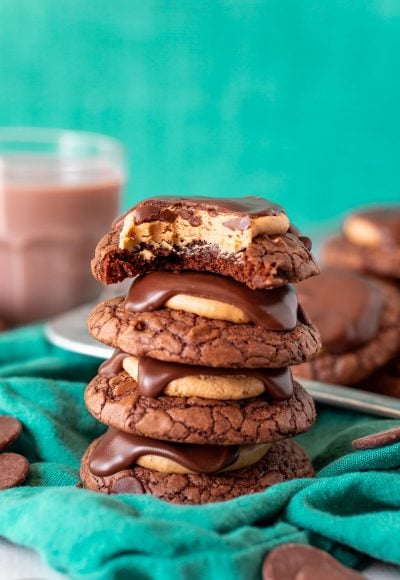 A stack of 4 brownie buckeye cookies on a green napkin.