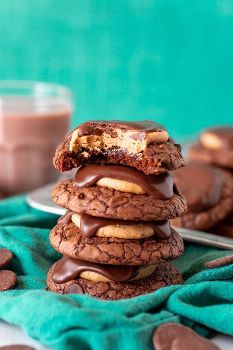 A stack of 4 brownie buckeye cookies on a green napkin.