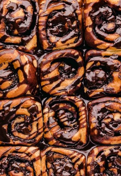 Overhead photo of cinnamon rolls covered in chocolate in the pan.