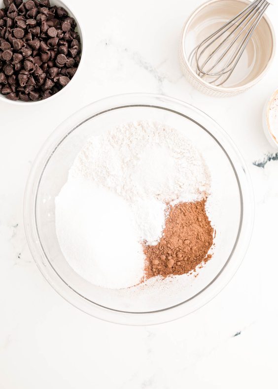 Dry ingredients for chocolate cake in a glass mixing bowl.