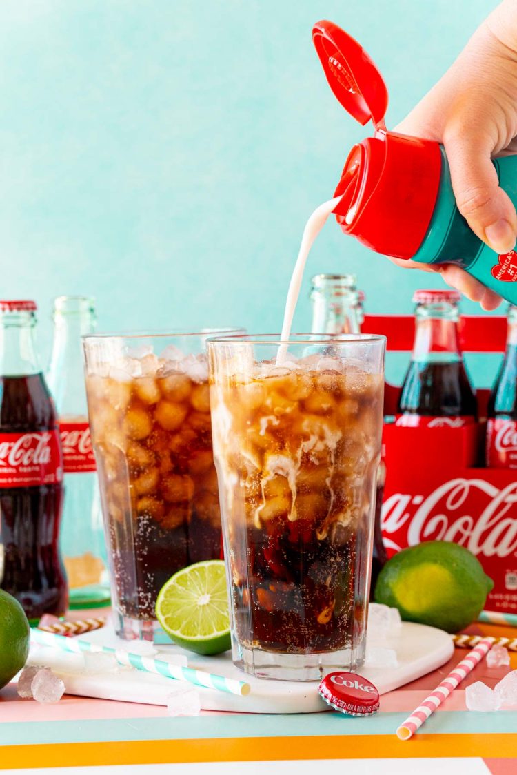Coconut coffee creamer being poured into a glass with ice and Coke.
