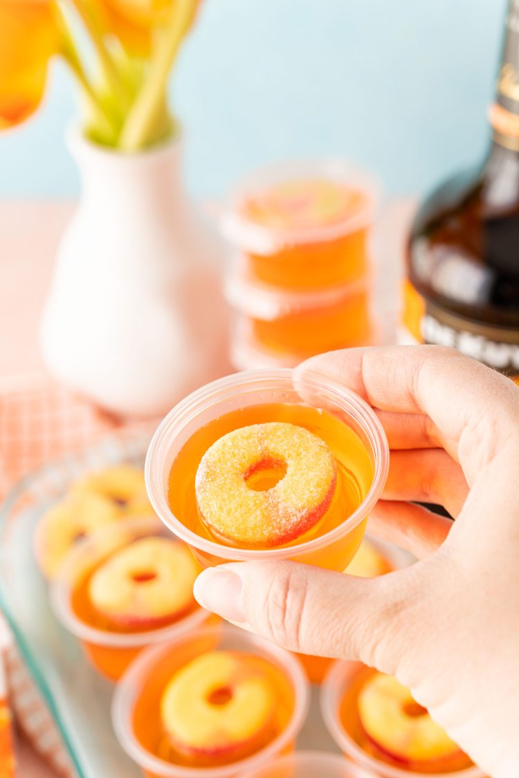 A woman's hand holding a jello shot to the camera.