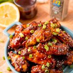 Close up photo of grilled Korean BBQ chicken wings on a blue serving plate.