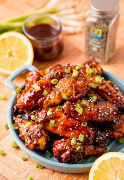 Close up photo of grilled Korean BBQ chicken wings on a blue serving plate.