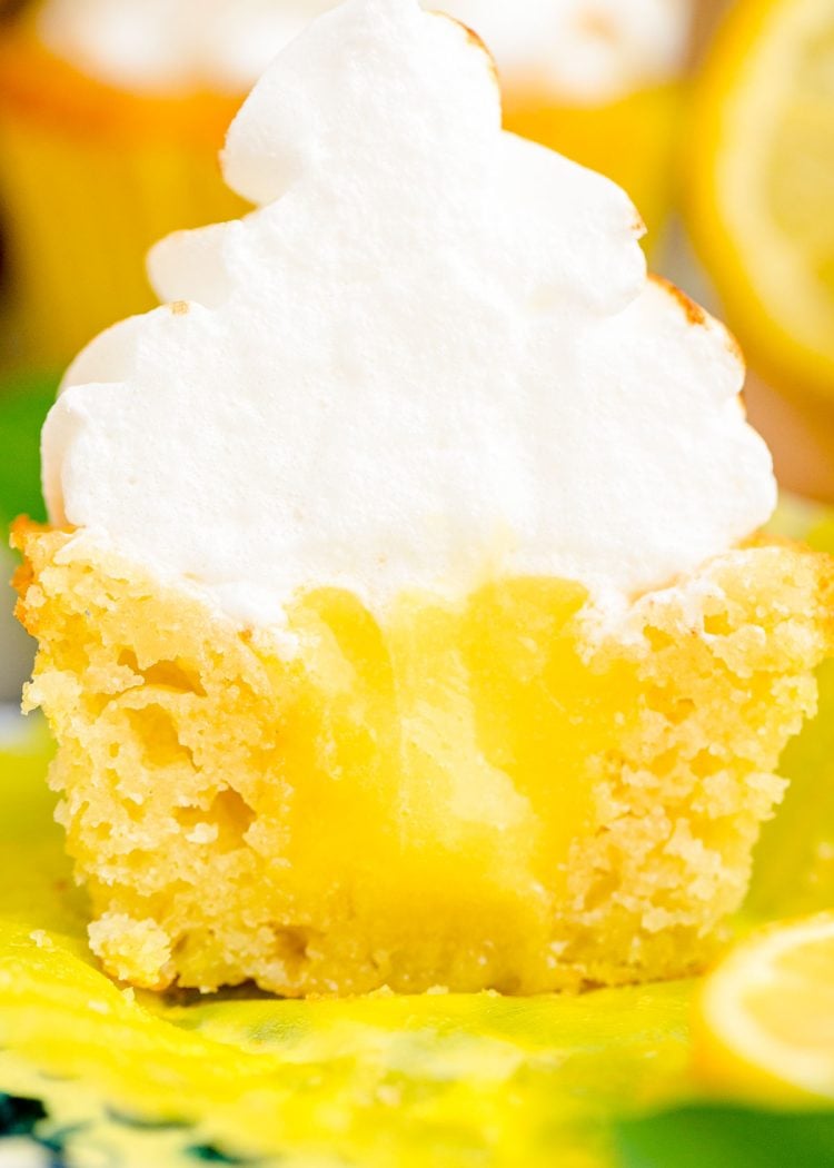 A lemon meringue cupcake cut in half to reveal lemon curd inside.