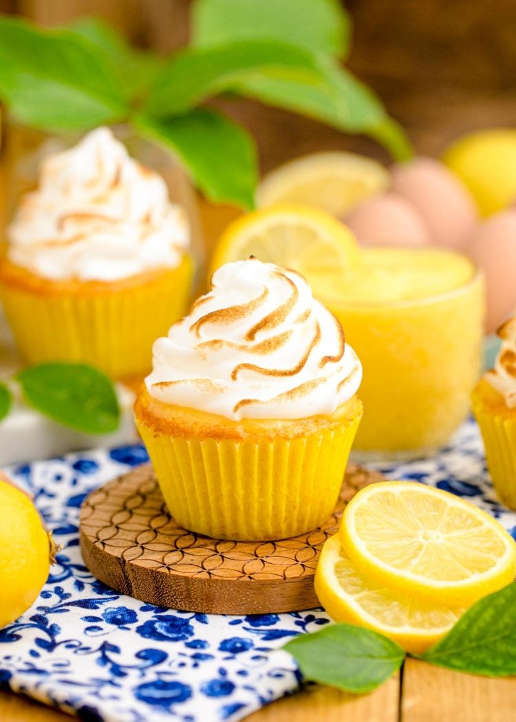 Close up photo of a lemon meringue cupcake on a wooden coaster.