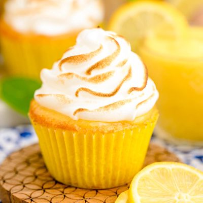 Close up photo of a lemon meringue cupcake on a wooden coaster.
