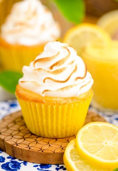 Close up photo of a lemon meringue cupcake on a wooden coaster.