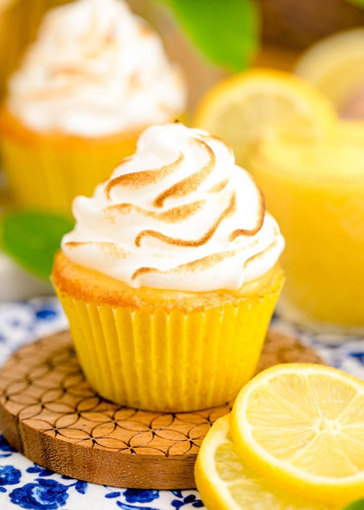 Close up photo of a lemon meringue cupcake on a wooden coaster.