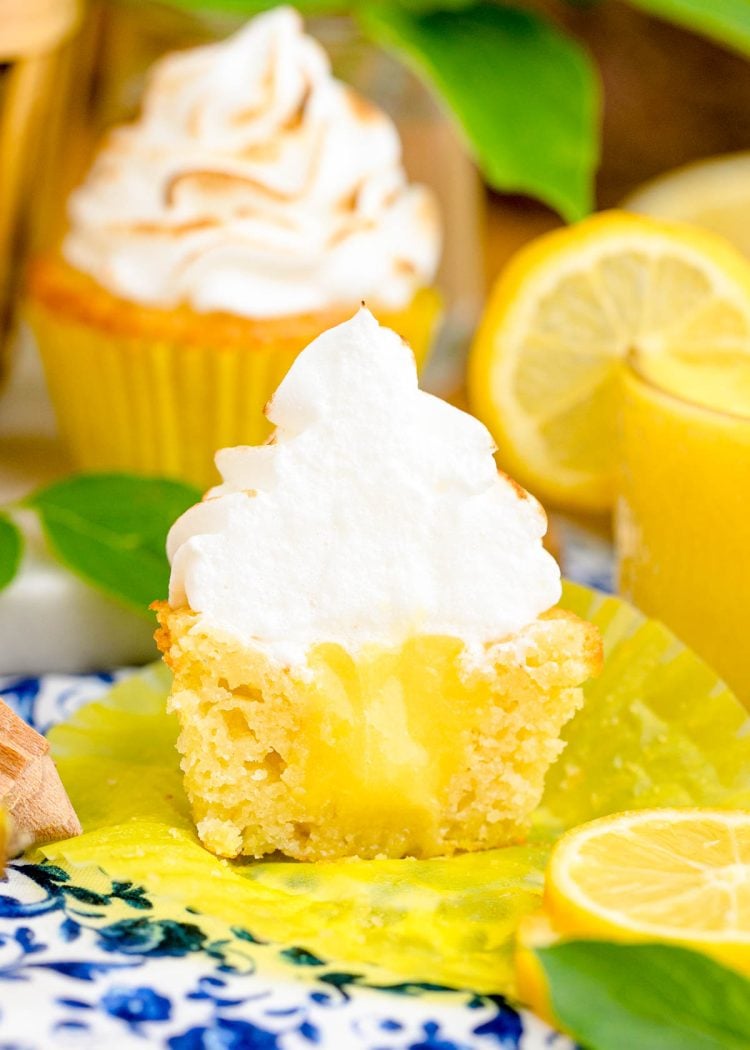A lemon meringue cupcake cut in half to reveal lemon curd inside.