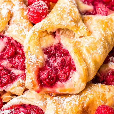 Close up photo of raspberry danishes piled on a plate.
