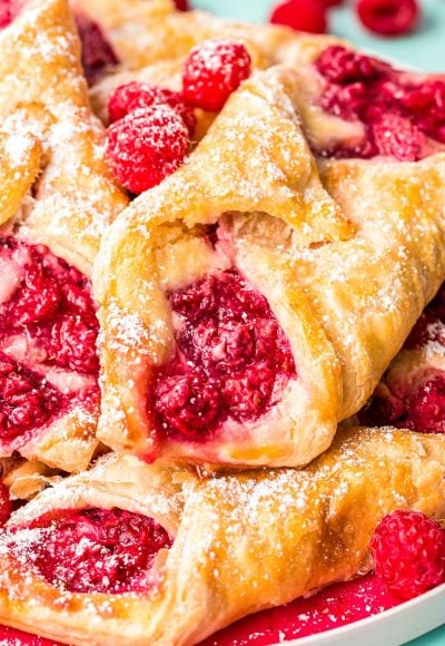 Close up photo of raspberry danishes piled on a plate.