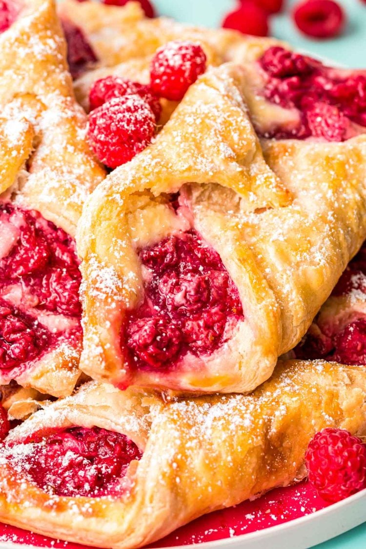 Close up photo of raspberry danishes piled on a plate.