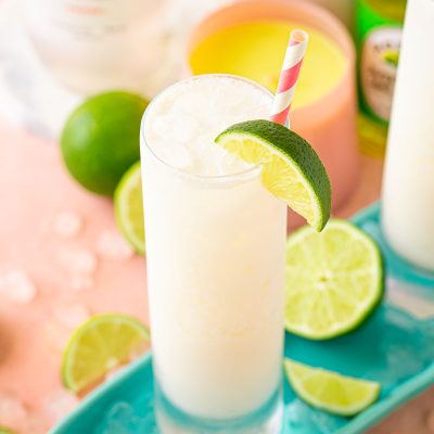 Close up of a RumChata Malibu Lime and Soda cocktail in a tall glass with limes around it.