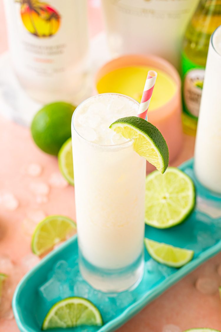 Close up of a RumChata Malibu Lime and Soda cocktail in a tall glass with limes around it.