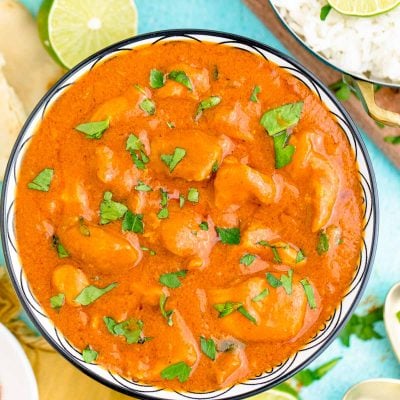 Overhead photo of slow cooker butter chicken in a blue bowl garnished with cilantro.