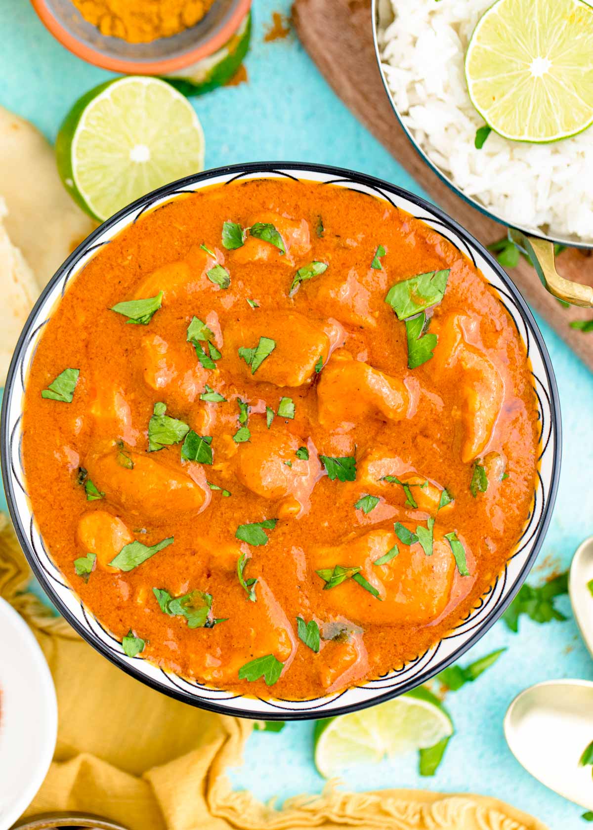 Overhead photo of slow cooker butter chicken in a blue bowl garnished with cilantro.