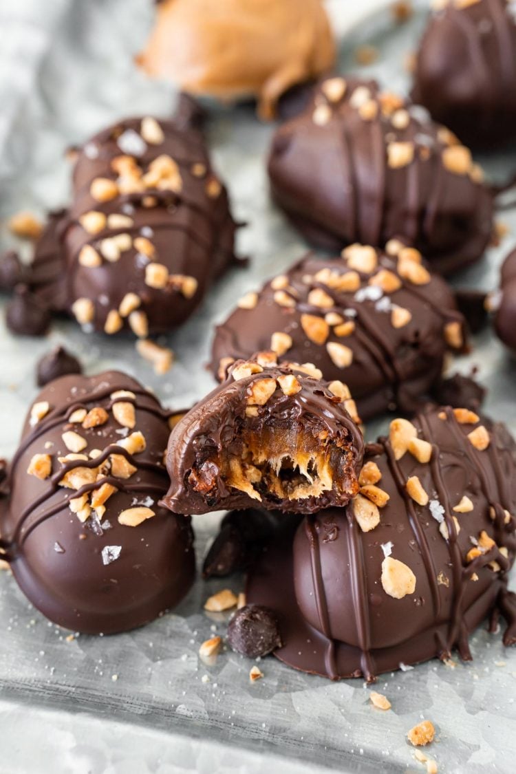 Snickers stuffed dates on a metal serving tray, one has a bite missing.