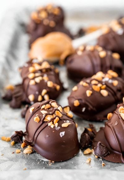 Close up photo of chocolate covered dates topped with chopped peanuts and flaky salt.