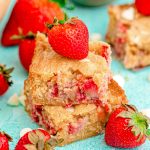 Close up photo of two strawberry blondies stacked on top of each other on a blue surface.