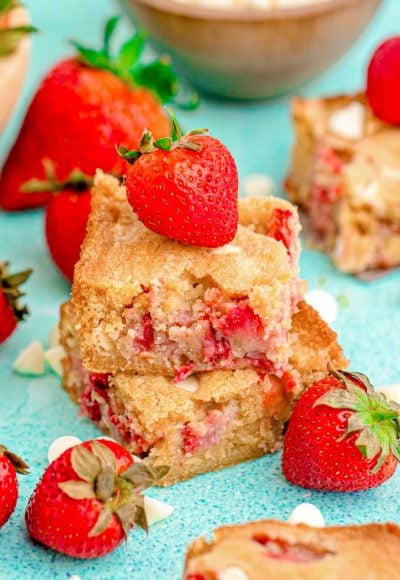 Close up photo of two strawberry blondies stacked on top of each other on a blue surface.