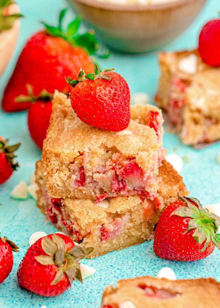 Close up photo of two strawberry blondies stacked on top of each other on a blue surface.