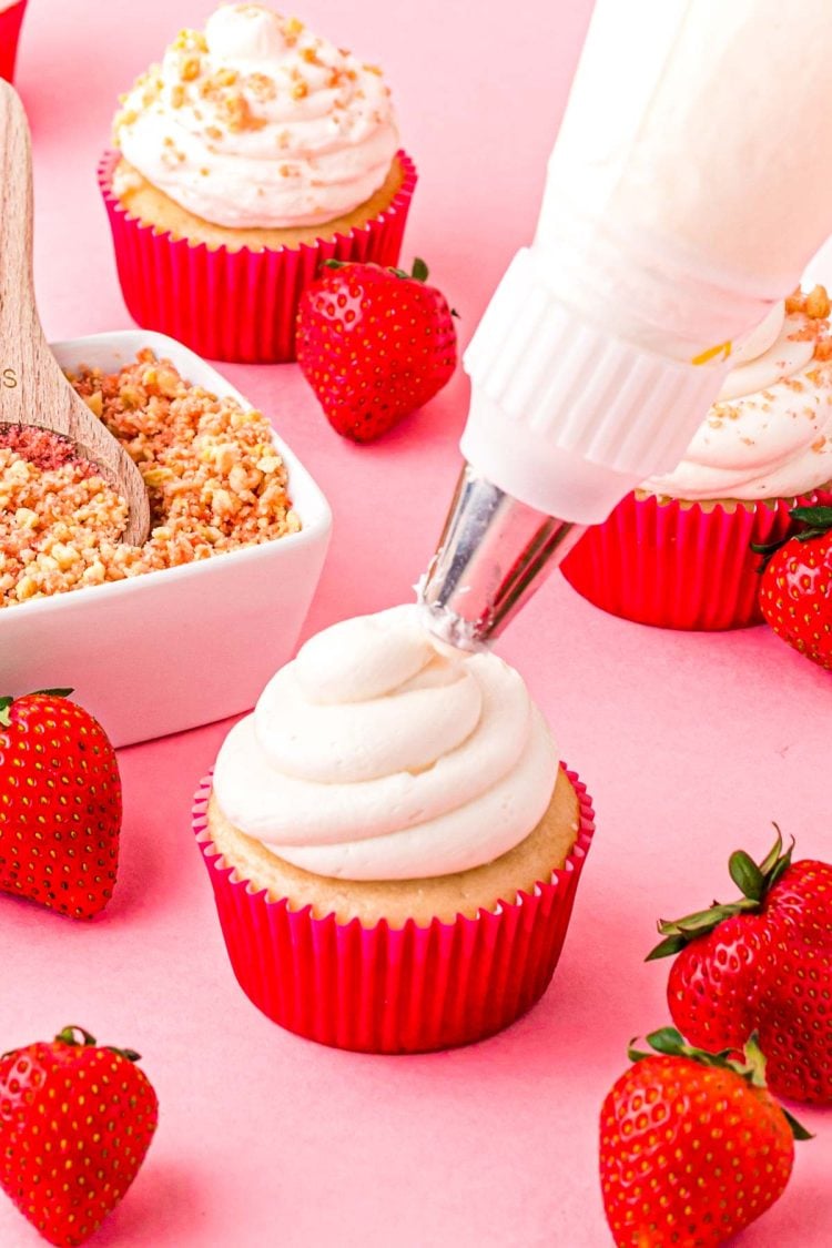 Frosting being piped on a cupcakes.