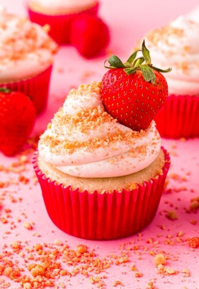 Close up photo of Strawberry Shortcake Cupcakes on a pink surface.