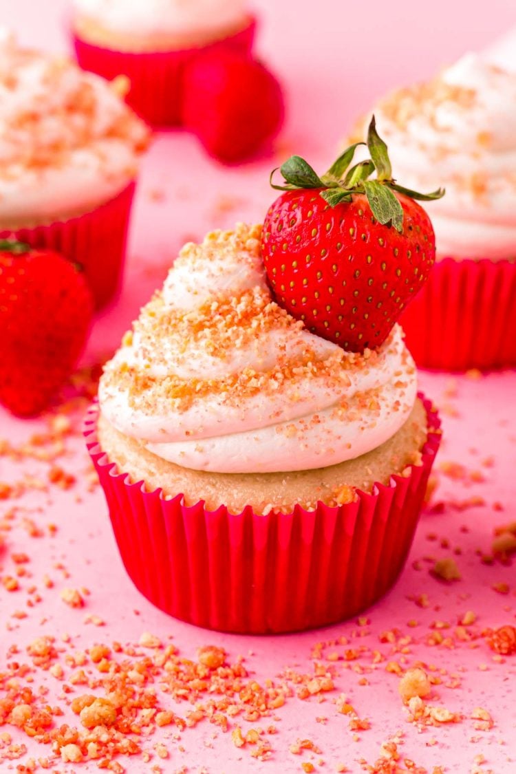 Close up photo of Strawberry Shortcake Cupcakes on a pink surface.