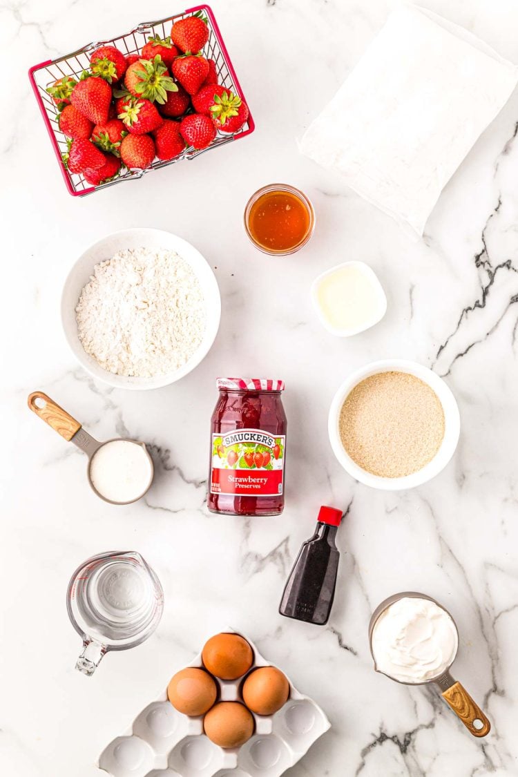 Ingredients to make strawberry shortcake cupcakes on a marble surface.