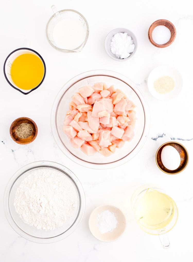 Ingredients to make homemade chicken nuggets on a marble surface.