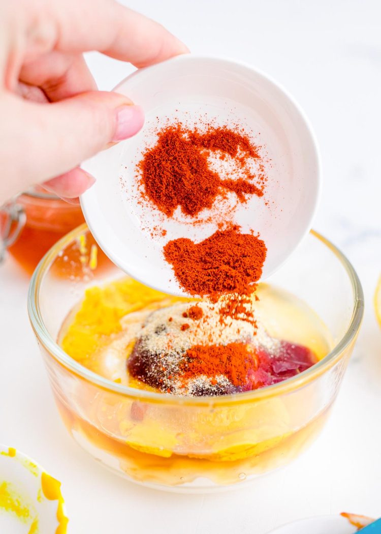 A woman's hand dumping spices into a bowl to make a dipping sauce.