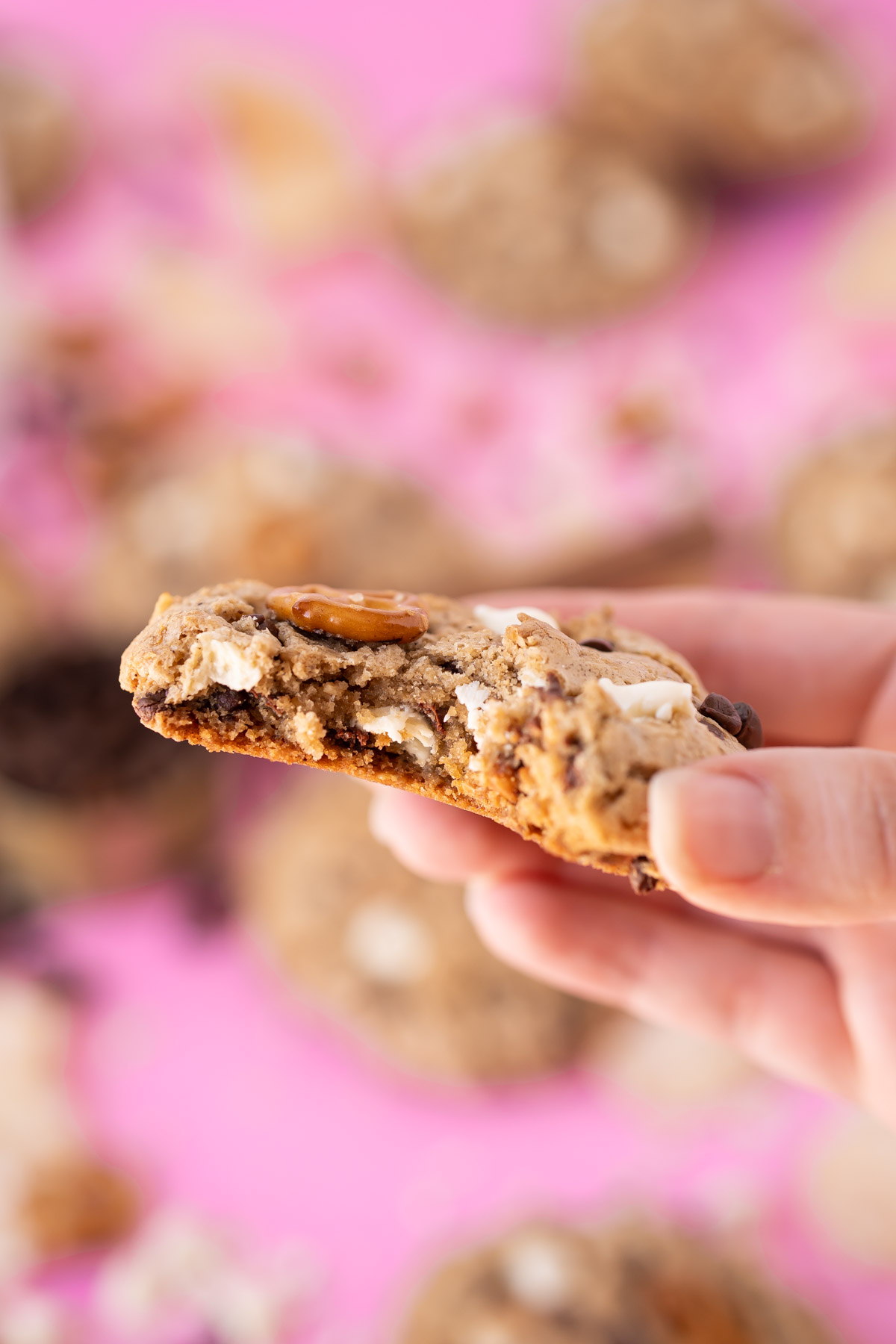 A woman's hand holding a compost cookie to the camera with a bite missing.