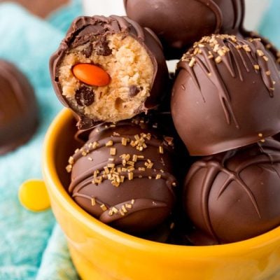 Close up photo of peanut butter cookie dough truffles in a yellow bowl, one truffle has a bite taken out.