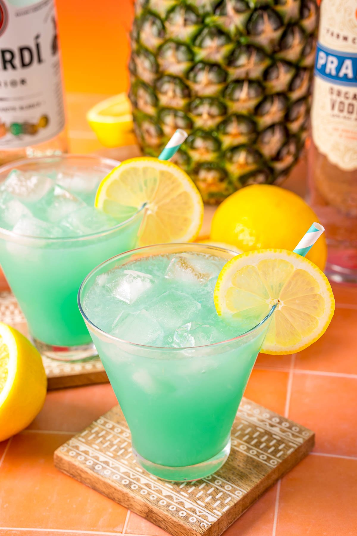 Two glasses of mermaid rum punch on an orange table.