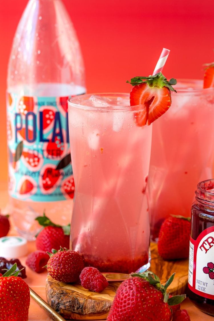 Close up photo of tiktok jam seltzer on a cutting board with strawberries and raspberries around it.